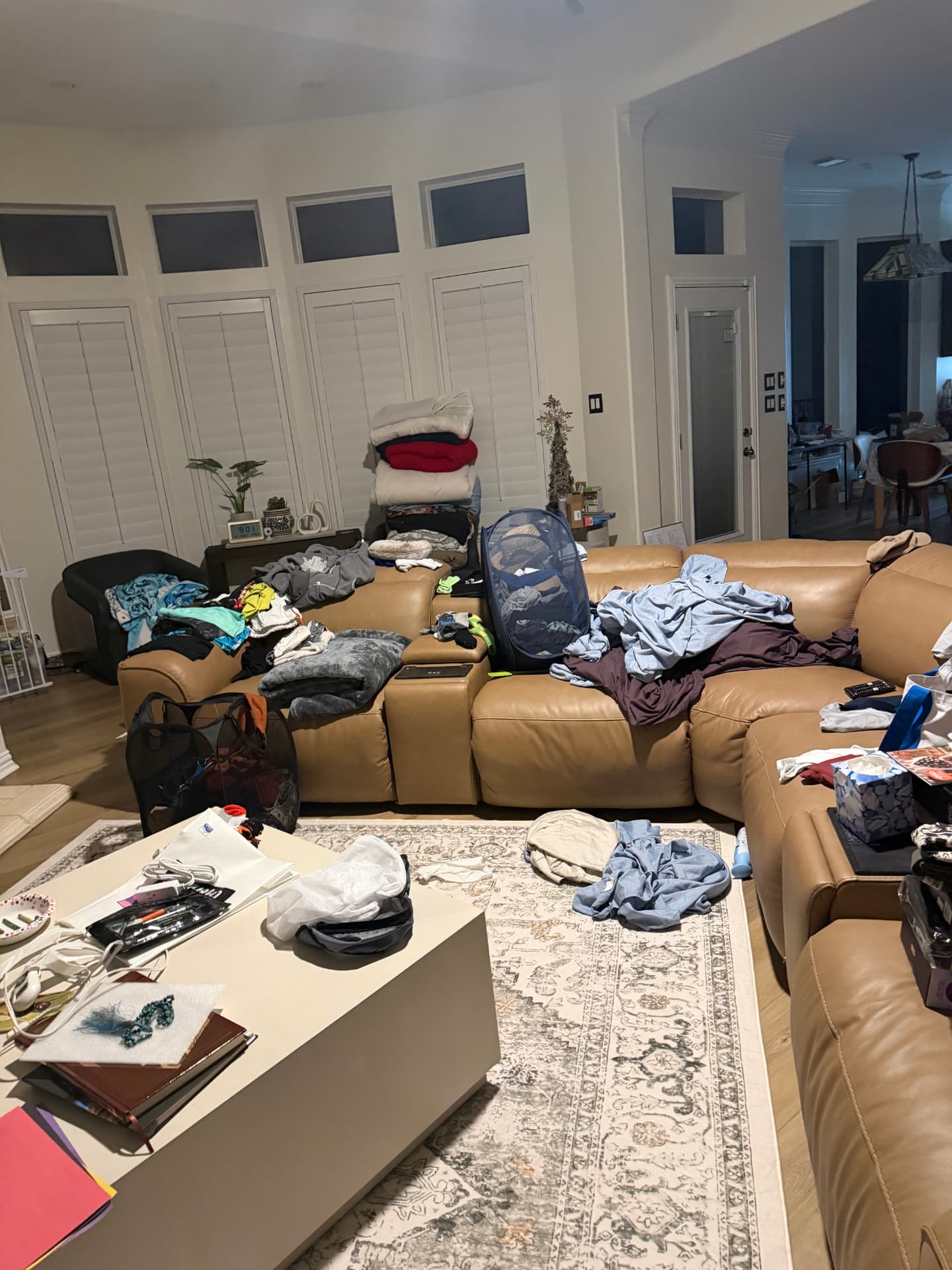 Living room before organizing with clothes piled on the sofa